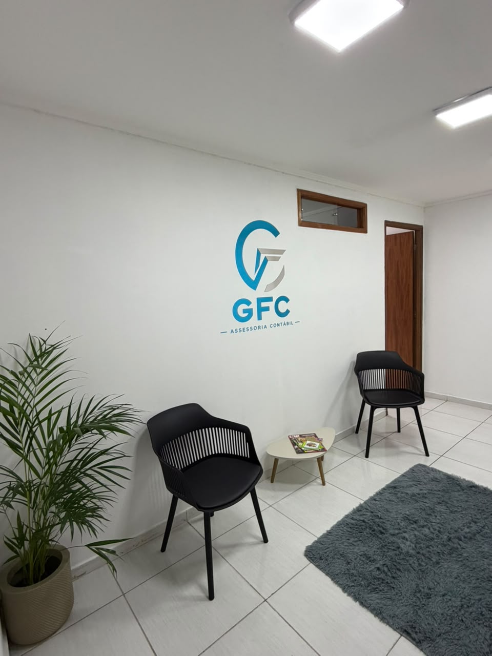 Recepção da GFC com poltronas, plantas e a marca na parede