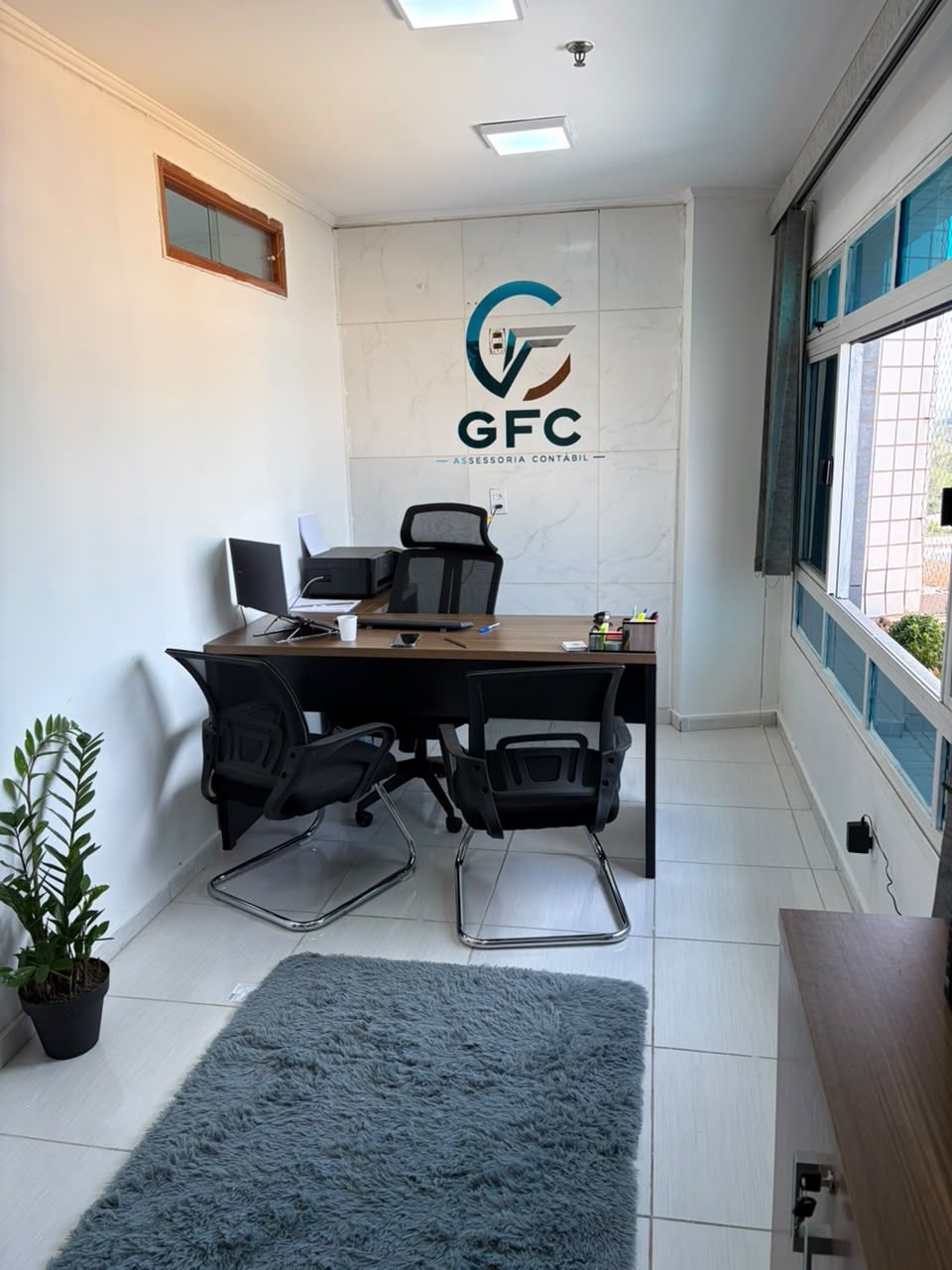 Sala da GFC com mesa de atendimento e cadeiras para clientes